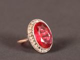 gros plan d'une bague avec une pierre rouge entourée de diamants