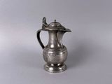 cafetière plaquée argent avec couvercle, posée sur une surface lisse