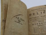someone is holding an old book with a signature on it