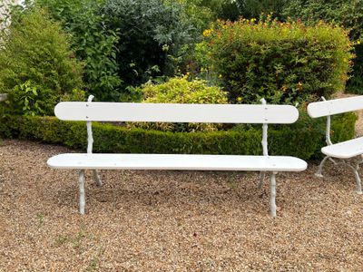 un banc blanc et une chaise blanche au milieu d'un jardin