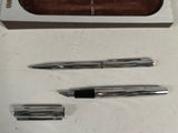 two pens and a pencil in a box on a table
