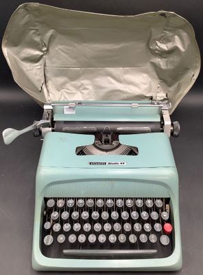 une machine à écrire bleue sur laquelle est posé un sac en papier