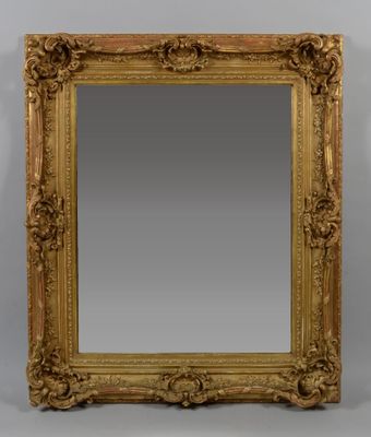 a gold framed mirror with ornate carvings on the edges