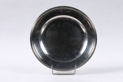 une assiette en argent posée sur un support, sur fond blanc