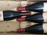 four bottles of wine in a cardboard box on a table