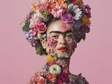 a woman with flowers in her hair and a pink background