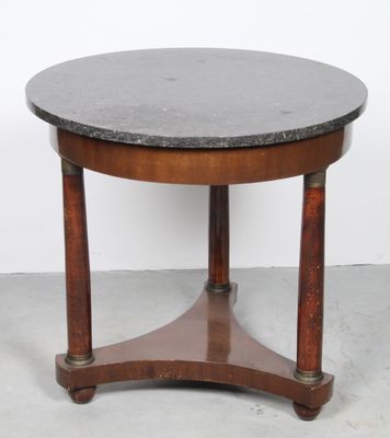 a round table with a black marble top and wooden legs