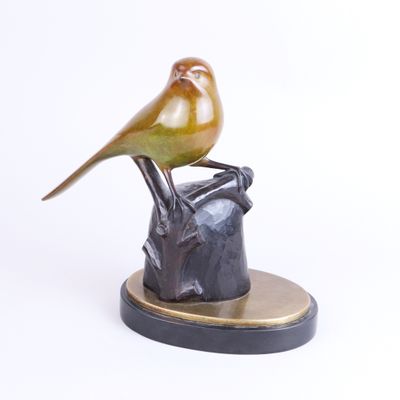 statue of a bird perched on top of a rock on a white surface