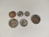 a group of five old coins sitting on top of a white surface