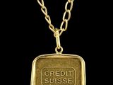 un pendentif en forme de lingot d'or muni d'une chaîne, sur fond noir