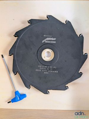 une lame de scie circulaire posée sur une table, à côté d'un outil bleu