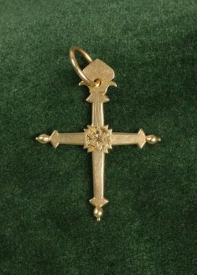 croix plaquée or sur velours vert, ornée d'un diamant au centre