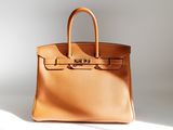 a brown leather handbag sitting on top of a white surface