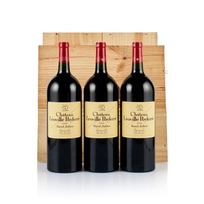 three bottles of red wine sit in front of a wooden crate