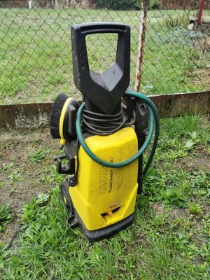 a yellow and black pressurer on the ground next to a fence