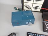 a blue electronic device sitting on a table next to a keyboard