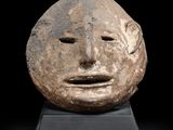 une tête d'homme sculptée dans la pierre, sur un fond noir