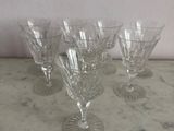 four wine glasses are lined up on a marble table