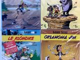 quatre albums de bandes dessinées exposés sur une table devant un fond blanc