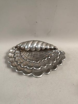 un plateau en argent orné d'un coquillage, posé sur une table