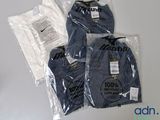 three t - shirts wrapped in plastic bags on a table