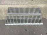 deux grilles métalliques posées par terre à côté d'un trottoir
