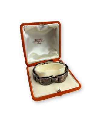 une photo d'un bracelet dans une boîte, posé sur une surface blanche