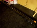 une photo d'une pièce avec un tapis de course et une télévision