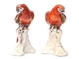 two figurines of parrots sitting on top of a tree stump