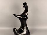 une sculpture noire représentant une personne assise sur une chaise