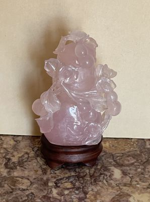 une statue en cristal rose posée sur une table en marbre
