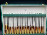 a green case with a bunch of knives and spoons in it