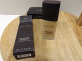 two bottles of makeup sitting on top of a wooden table