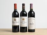 three bottles of wine are lined up on a wooden table