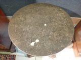 a small round table with a marble top on a tiled floor