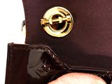 a person holding a black purse with a gold buckle