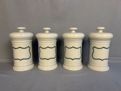 three white ceramic jars with green trims on them on a gray surface