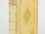 an old book sitting on top of a white table next to a white wall