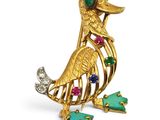 a close up of a gold bird brooch with multi colored stones