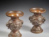 paire de vases en bronze munis d'anses, posés sur des socles, sur un fond gris