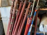 de nombreuses battes de baseball empilées sur une étagère dans un garage