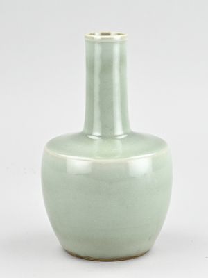 un vase vert posé sur une surface blanche