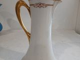 a white and gold coffee pot sitting on a table