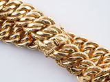 gold chain bracelet on a white surface with a white background