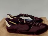 une paire de chaussures violettes posées sur un sac marron muni d'une étiquette