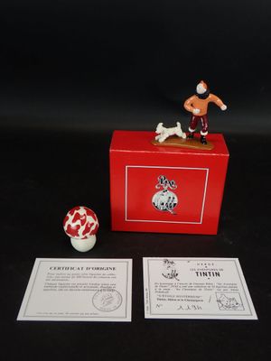 une petite figurine posée sur une boîte rouge
