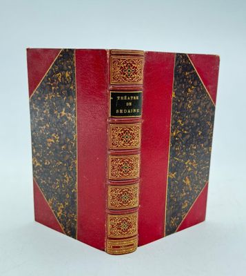 un vieux livre à la couverture rouge et à la bordure dorée