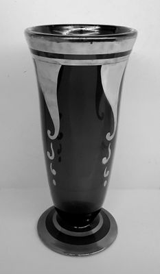 a black vase sitting on a table with a white wall in the background