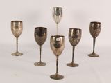 six silver goblets are lined up in a row on a white surface
