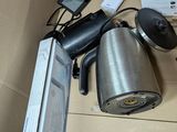 a box with a coffee pot, a remote control, a cell phone, and other items in it